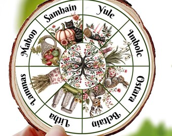 May include: A round wooden coaster featuring a seasonal wheel design with illustrations and text. The coaster has a natural wood grain edge and is held against a backdrop of green foliage. The design includes images of pumpkins, flowers, and other seasonal elements.