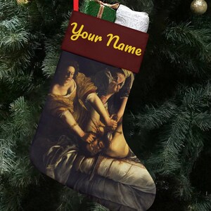 Puede incluir: Un calcetín navideño con un puño burdeos y una pintura de figuras. El puño tiene el texto "Your Name" en letras amarillas. El calcetín está colgado de un árbol de Navidad con adornos rojos y dorados.