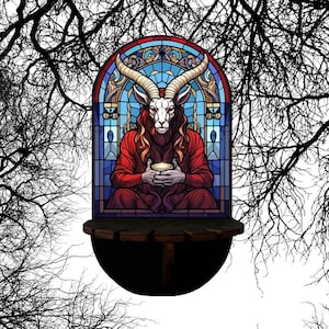 May include: A stained glass window featuring a goat-like figure in a red robe holding a cup. The window has a blue and gold border and is set against a backdrop of bare tree branches. The figure has large horns and is seated.