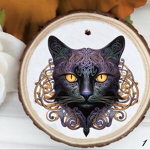 May include: A wooden round ornament with a black cat with purple and gold intricate designs. The cat's eyes are yellow.