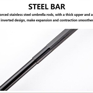 K&ouml;nnte beinhalten: Nahaufnahme einer schwarzen Stahlstange, Teil eines Regenschirms. Der Text "STEEL BAR" steht oben. Die Beschreibung besagt, dass sie verst&auml;rkte Regenschirmstangen aus Edelstahl hat.