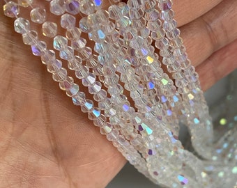 May include: A strand of iridescent clear glass beads. The beads are faceted and have a hexagonal shape.