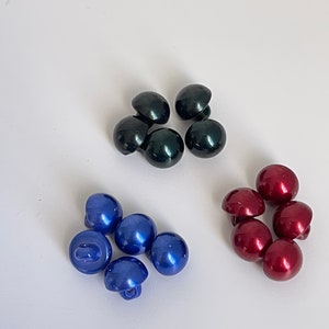 Peut inclure: Assortiment de boutons en plastique de trois couleurs : vert foncé, bleu et bordeaux. Les boutons sont ronds et ont une finition brillante.
