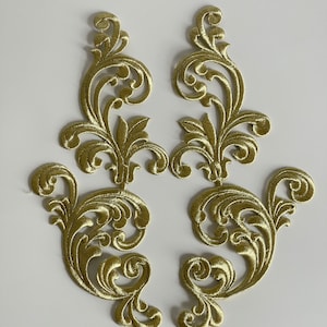 Peut inclure: Deux appliques en tissu brodées dorées avec un motif floral. Les appliques sont complexes et détaillées, avec un motif délicat et tourbillonnant.