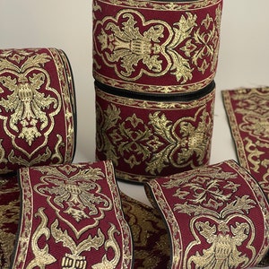 May include: Burgundy and gold trim with a floral pattern. The trim is rolled up on a spool.