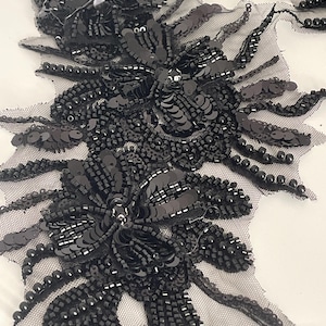 Peut inclure: Applique florale noire, ornée de perles et de sequins, sur un support en résille transparente. L'applique présente des motifs floraux détaillés avec des perles et des sequins scintillants. Idéal pour embellir des vêtements ou des accessoires.