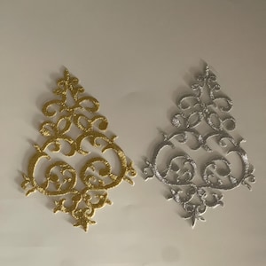 May include: Two embroidered tree-shaped appliques. One is gold, the other is silver. Each applique features an ornate, swirling design. The appliques are likely for crafting or embellishment purposes.