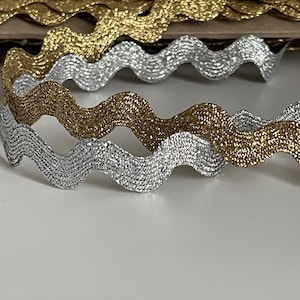 Puede incluir: Dos rollos de ribete ondulado brillante. Un rollo es plateado y el otro es dorado.