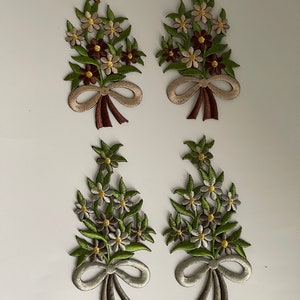 Könnte beinhalten: Vier gestickte Blumensträuße mit Schleifen. Zwei Sträuße sind braun, weiß und gold. Zwei Sträuße sind grün, weiß und gold.
