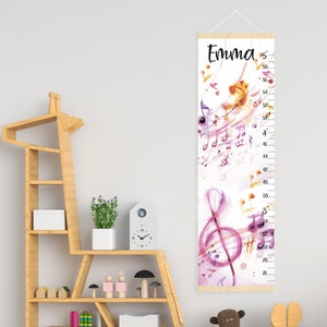 Puede incluir: Un gráfico de crecimiento de madera blanca con un diseño de acuarela de notas musicales y una clave de sol. El gráfico está etiquetado como "Emma" y tiene medidas en pulgadas de 26 a 58 pulgadas.