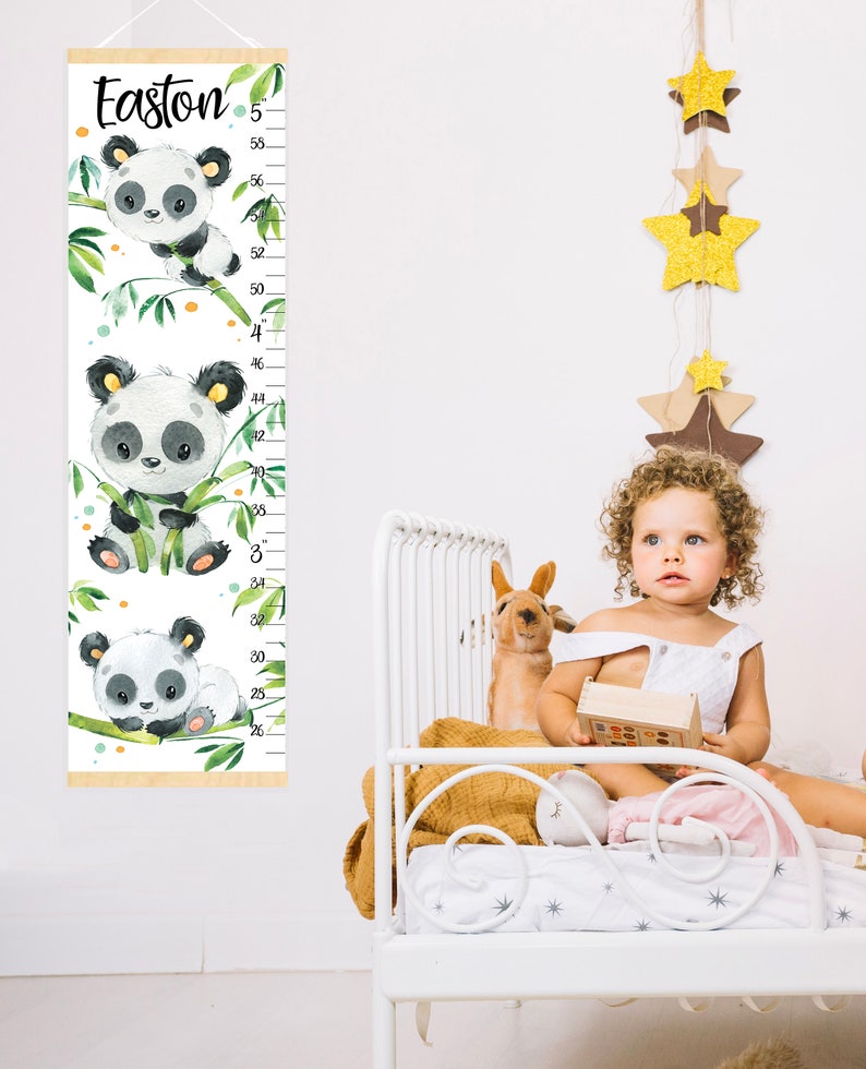May include: A white growth chart with a wooden frame and a panda bear design. The chart features a panda bear holding bamboo and a measurement scale from 25 inches to 58 inches. The chart is labeled "Easton".