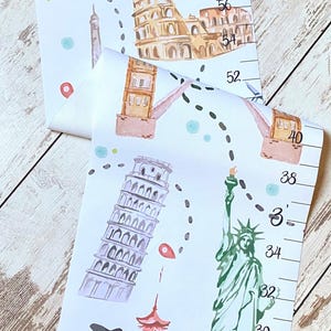 Puede incluir: Un medidor de altura de lona blanca que cuelga de una varilla de madera con una cuerda. Presenta el nombre Scarlett, una ruta de viaje punteada e ilustraciones en acuarela del Coliseo, la Torre de Pisa, la Estatua de la Libertad y una pagoda.