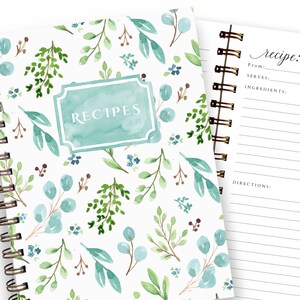 May include: A spiral-bound recipe journal with a watercolor floral design. The cover features a teal label with the word "RECIPES" and is adorned with green and blue leaves. The open page displays a recipe template with prompts for ingredients and directions.