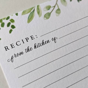 K&ouml;nnte beinhalten: Eine wei&szlig;e Rezeptkarte mit einem gr&uuml;nen Aquarell-Blumendesign oben. Der Text "REZEPT: aus der K&uuml;che von:" ist auf die Karte gedruckt.
