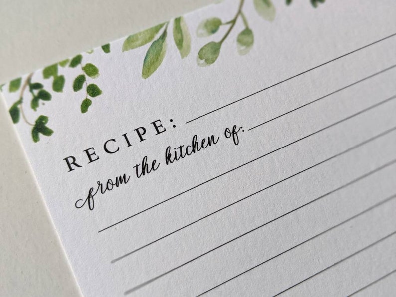 K&ouml;nnte beinhalten: Eine wei&szlig;e Rezeptkarte mit einem gr&uuml;nen Aquarell-Blumendesign oben. Der Text "REZEPT: aus der K&uuml;che von:" ist auf die Karte gedruckt.