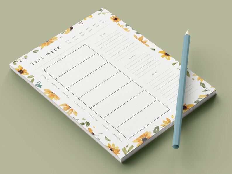 May include: A weekly planner notepad with a sunflower and floral design. The notepad has a white background with black text and lines. The text "This Week" is at the top of the notepad. The days of the week are listed below the text. The notepad is surrounded by a border of sunflowers and floral designs.