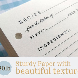 May include: A stack of white recipe cards with a hole punched in the top corner. The cards have lines for writing down a recipe, including the name, ingredients, servings, and prep time. The text "RECIPE: from the kitchen of:" is printed on the card. The cards are made of sturdy paper with a beautiful texture. The text "80lb" is printed on a blue circle.