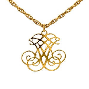 May include: A gold chain necklace with a large, intricate pendant featuring a stylized letter 'W' design.