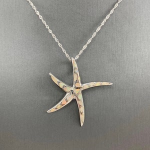 May include: A silver starfish pendant necklace. The pendant has a textured surface and is suspended from a delicate chain. The starfish design is a classic nautical theme, perfect for beach lovers.