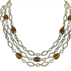 May include: A gold chain necklace with three strands and brown oval-shaped beads.