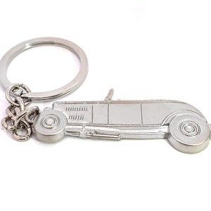 May include: Silver-toned metal keychain featuring a detailed model of a classic hot rod car. The keychain has a split ring for attaching keys.