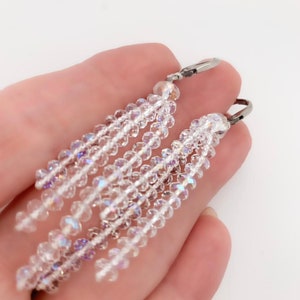 May include: A pair of crystal dangle earrings with silver hooks. The earrings are made of clear crystal beads that are strung together in a cascading design.