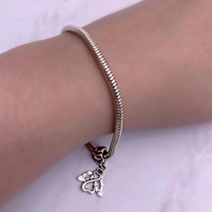 May include: A silver snake chain bracelet with a small angel charm with clear crystals.