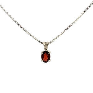 May include: A silver chain necklace with a pendant featuring a red oval-shaped gemstone.