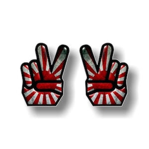May include: Two peace sign hand stickers with a red and white Japanese flag design.