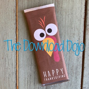 May include: A brown candy bar wrapper with a cartoon turkey design. The turkey has large white eyes, a yellow beak, and a red wattle. The words "HAPPY THANKSGIVING" are printed in white at the bottom. The text "The Download Dojo" is written in blue.