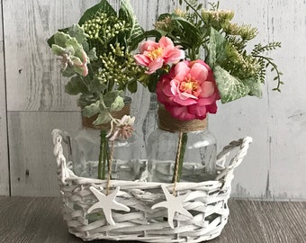 Beachy Looking Rope Covered Vases In A White Wicker Carrier With Flowers And Succulents