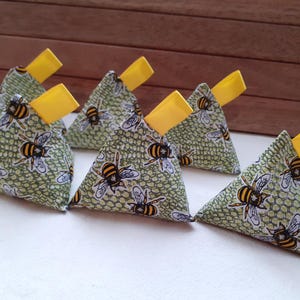 May include: Six green and yellow triangular fabric pouches with a bee pattern. The pouches have yellow ribbon ties.