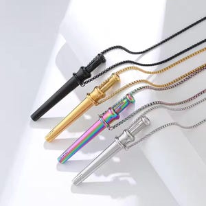 May include: Four pendant necklaces featuring long, cylindrical, wand-like charms with a flared top section and a series of small dots at the base. The set includes one black, one gold-tone, one iridescent rainbow, and one silver-tone metal finish.