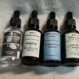 May include: Four small glass bottles with dropper tops containing beard oil. The bottles are labeled with the brand name "Bath & Cauldron Works" and the scent of each beard oil: "Fictional Bad Boy", "Beard Oil", "Forgotten Forest", and "Loch Ness".