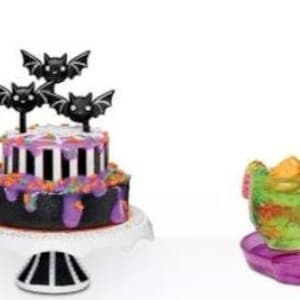 Pode incluir: Um conjunto de cinco miniaturas de alimentos com tema de Halloween, incluindo um bolo com morcegos, um barco com um monstro, dois copos de bebidas verdes com canudos e duas sobremesas de chocolate com vermes de goma.