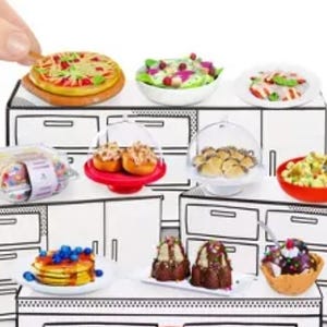 Puede incluir: Un juego de cocina en miniatura blanco con una variedad de alimentos en miniatura, que incluyen pizza, ensalada, cupcakes y helado. La cocina tiene gabinetes y cajones blancos.