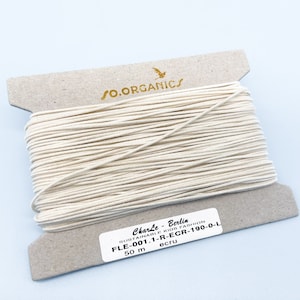 May include: A spool of ecru-colored thread, labeled "Charle Berlin Sustainable Kids Fashion FLE-001.1-R-ECR-190-0-L 50 m ecru".