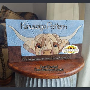 May include: A rectangular Kinusaiga pattern craft project featuring a Highland cow with long horns against a light blue background. The text reads Kinusaiga Pattern, Front Porch Studio, All of my patterns are drawn by hand, never AI, and Digital Download, Basic Instructions Included.