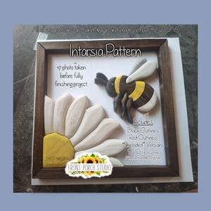May include: A wooden intarsia pattern project in a dark brown frame featuring a carved wooden bee and flower petals. Text on the display reads: Intarsia Pattern, photo taken before fully finishing project, Includes Black Outlines Red Outlines Exploded Versions.