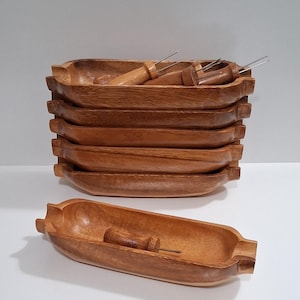 May include: A set of seven wooden corn-shaped serving dishes. Each dish is a warm brown color and includes a wooden handle with a metal pick. One dish is displayed separately, showcasing the design.