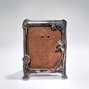 May include: A white ceramic mug with a black handle and the text "But First, Coffee" in a black, handwritten-style font. The mug is on a white surface.