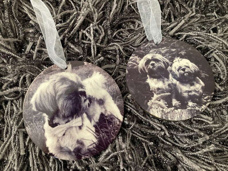 May include: Two round ornaments with black and white photos of dogs. One ornament features a single dog with a bow tie, while the other ornament features two dogs.