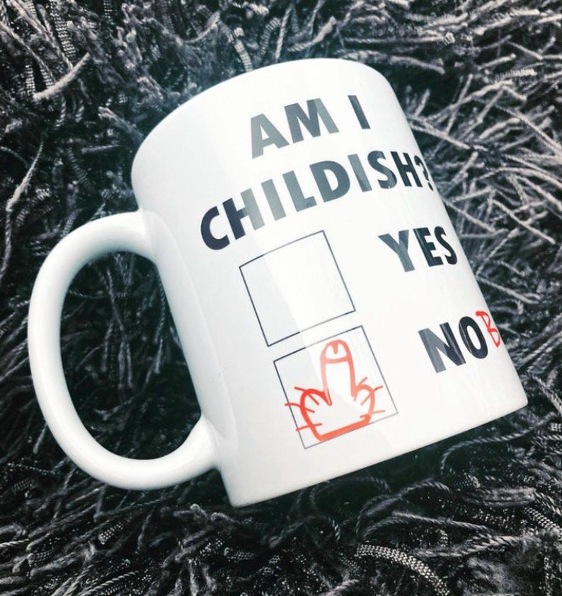 K&ouml;nnte beinhalten: Wei&szlig;e Keramiktasse mit schwarzem Text, der "Am I Childish?" lautet, mit einem Kontrollk&auml;stchen und den W&ouml;rtern "Yes" und "No" daneben. Das K&auml;stchen "No" ist angekreuzt, mit einem roten Mittelfinger, der darin gezeichnet ist.