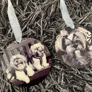 May include: Two round ornaments with black and white photos of Shih Tzu dogs. One ornament features a single dog looking at the camera, while the other ornament features two dogs sitting on a bench.