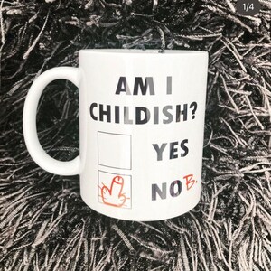 K&ouml;nnte beinhalten: Eine wei&szlig;e Keramiktasse mit dem Text "Am I Childish?" und einem Kontrollk&auml;stchen mit zwei Optionen: "Yes" und "No" mit einem Mittelfinger, der neben der Option "No" gezeichnet ist.