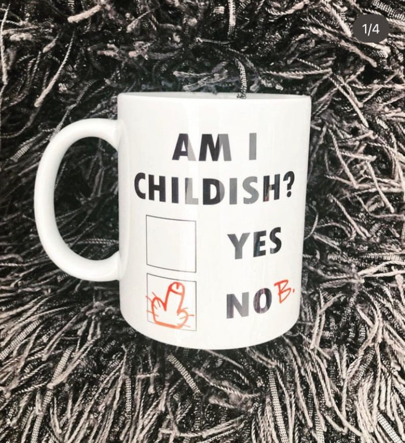 K&ouml;nnte beinhalten: Eine wei&szlig;e Keramiktasse mit dem Text "Am I Childish?" und einem Kontrollk&auml;stchen mit zwei Optionen: "Yes" und "No" mit einem Mittelfinger, der neben der Option "No" gezeichnet ist.