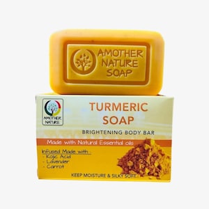 May include: A yellow turmeric soap bar with the text "AMOTHER NATURE SOAP" on top of a box. The box reads "TURMERIC SOAP BRIGHTENING BODY BAR" and lists ingredients like Kojic Acid and Carrot. The soap is designed to keep moisture and make skin silky soft.