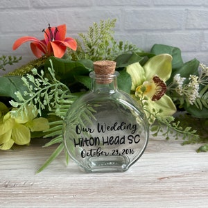 May include: A clear glass bottle with a cork top and a black label that reads "Our Wedding Hilton Head SC October 29, 2016".