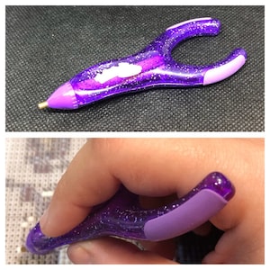 May include: Purple diamond painting tool with a clear plastic handle and a purple rubber grip. The tool has a small metal tip for picking up diamonds.