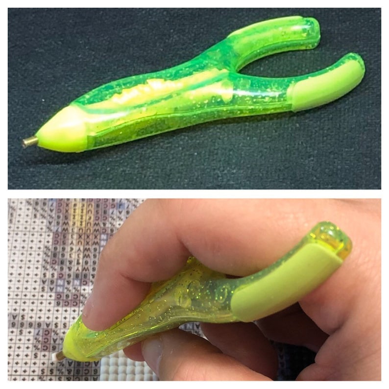 May include: A green diamond painting pen with a clear plastic body and a rubber grip. The pen has a small metal tip for picking up diamonds.